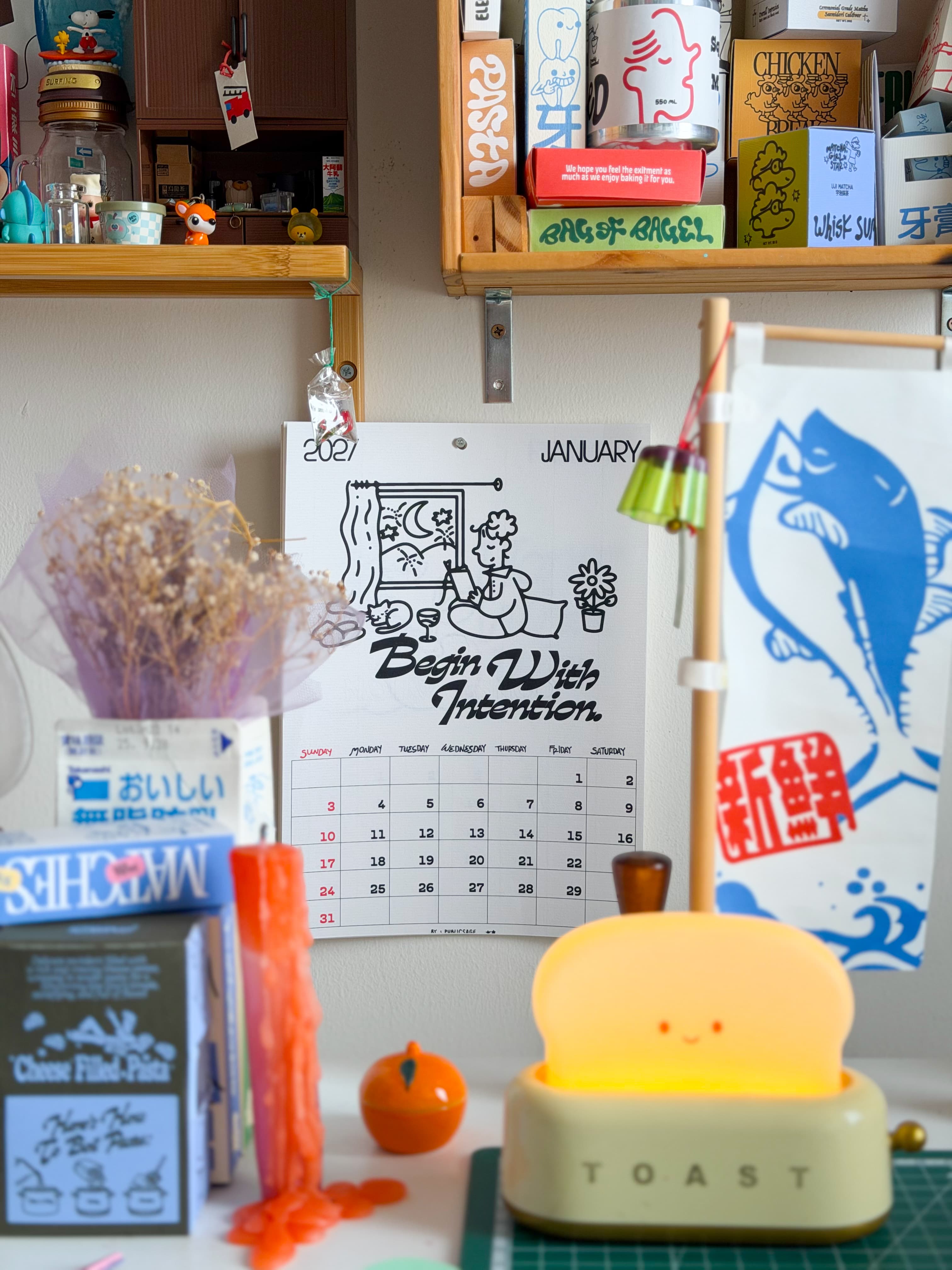 2027 wall calendar hanging on a shelf beside a toast lamp